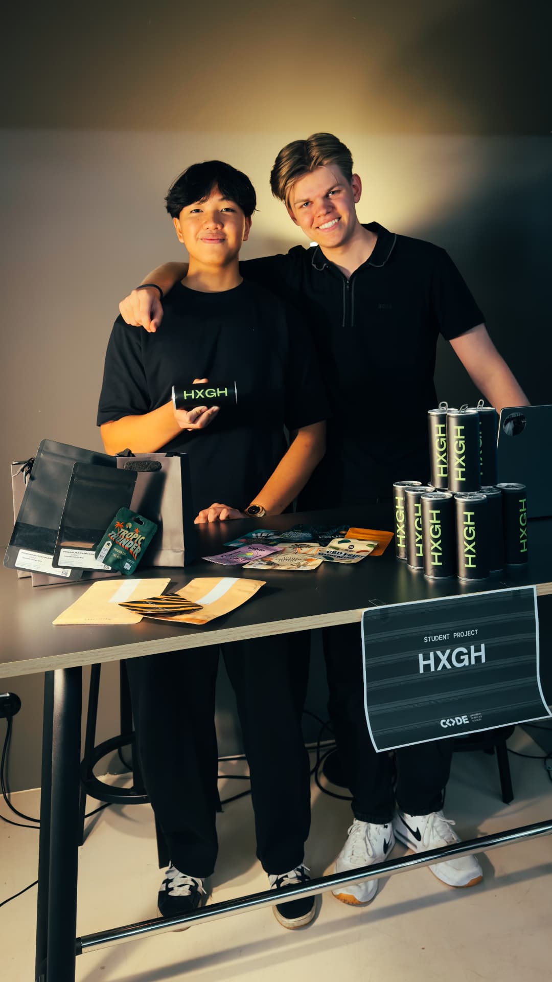 Sandro and his co-founder at the HXGH student project stand with branded products